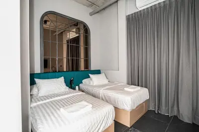 two beds in a room with a mirror at Chainam-Charmchuree residences cafe and spa in Ban Bang Bua Thong