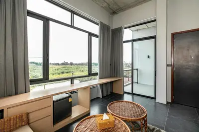 a room with a table and chairs and windows at Chainam-Charmchuree residences cafe and spa in Ban Bang Bua Thong