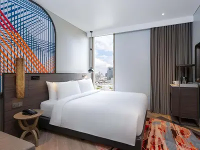 a bedroom with a white bed and a large window at Mercure Bangkok Surawong in Bangkok