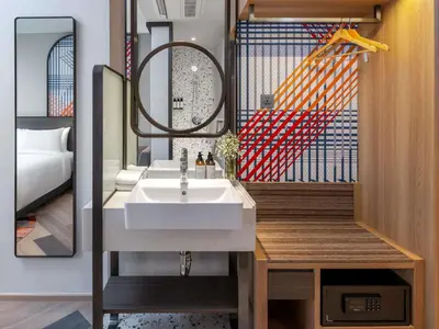 a bathroom with a sink and a mirror and a bed at Mercure Bangkok Surawong in Bangkok