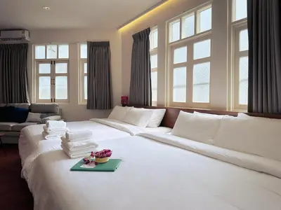 a large white bed in a room with windows at Belivin99 Residence Chinatown in Bangkok