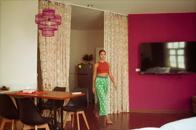 a woman standing in a room with a pink wall at Belivin99 Residence Chinatown in Bangkok