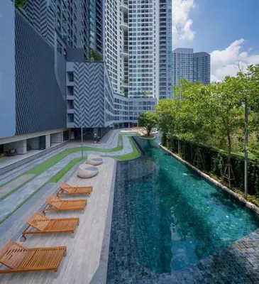 a swimming pool with lounge chairs in a city at Ideo O2 BTS Bangna in Bangkok