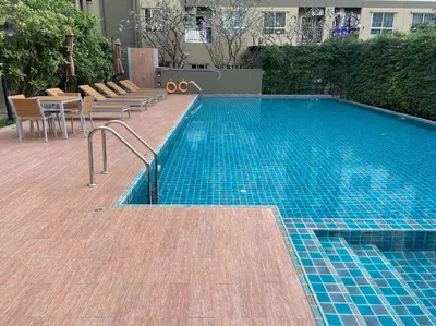 a swimming pool with chairs next to a building at Garden Oasis Apartment: Condo Near Bangkok River in Ban Sai Ma