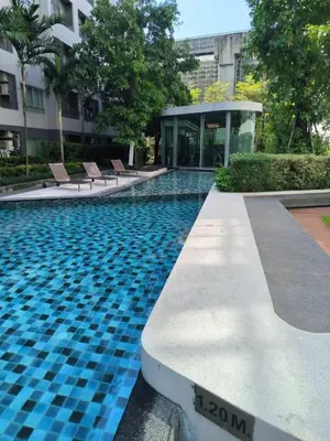 a swimming pool with chairs in front of a building at Elio Sukhumvit 64: Chic Space in Bangkok