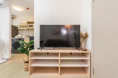 a living room with a television on a tv stand at Elio Del Ray BTS Punnawithi in Bangkok