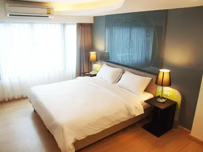 a bedroom with a large white bed and two lamps at Grand Tower Inn Sathorn Hotel in Bangkok