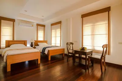 a bedroom with two beds and a table and chairs at Thaihome Resort in Ban Bang Muang