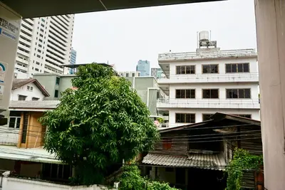 a tree in the middle of a city with buildings at Sathon 15 apartment close to BTS Skytrain St Louis & Surasak in Bangkok