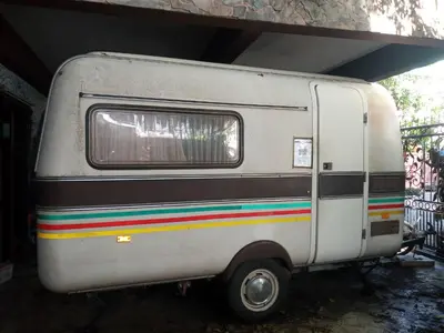 a white trailer with rainbow stripes parked under a building at Caravan & Smart in Bangkok