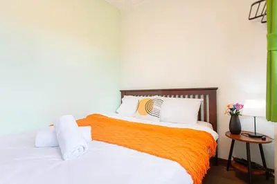 a bedroom with two beds with orange and white pillows at Friend House BKK in Bangkok