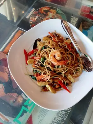 a bowl of noodles with shrimp and vegetables with a fork at Bang lumphu house&bistro in Bangkok