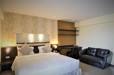 a bedroom with a large bed and a leather chair at Chateau de Sukhumvit in Bangkok