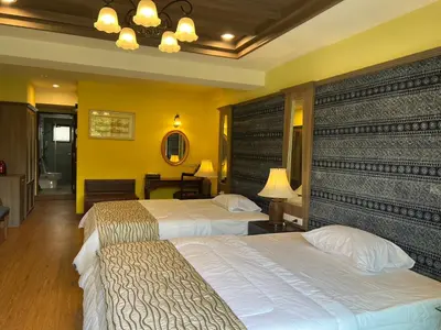 two beds in a hotel room with yellow walls at Quinstel Guesthouse in Bangkok