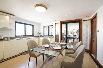 a kitchen and dining room with a glass table and chairs at Rooftop Paradise & Koi Pond-6BR Hideaway@Icon Siam in Bangkok