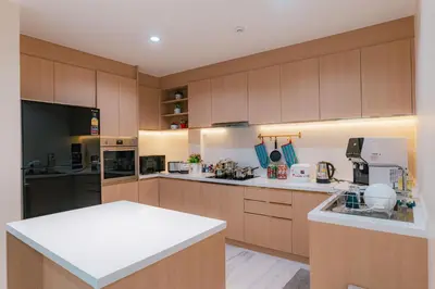 a large kitchen with wooden cabinets and white counter tops at PRIME SUKHUMVIT MODERN HOME, Phrom Phong BTS, Em District, Up to 14 guests in Bangkok