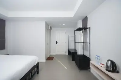 a bedroom with a white bed and a black cabinet at Mitr Inn Mrt Samyot Station - The Grand Palace in Bangkok
