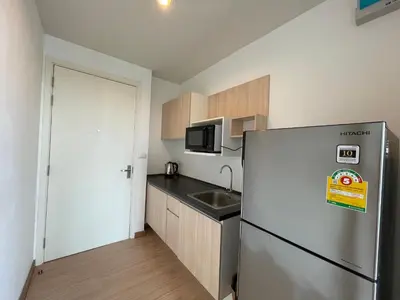 a small kitchen with a refrigerator and a sink at 1BR Apartment in Bangkok