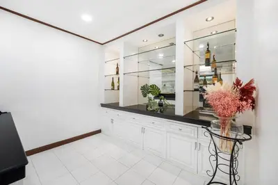 a kitchen with white cabinets and a vase of flowers at MIQ HK16 - 3BR Huai Khwang MRT with Pool Table near Jodd Fair in Ban Zong Katiam