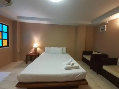 a bedroom with a large white bed and a couch at Bangkok Travel Suites Hotel in Nonthaburi