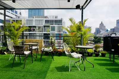 a patio with chairs and tables on the grass at Silom Soi 3 Hash Apartment hip and funky with rooftop view in Bangkok