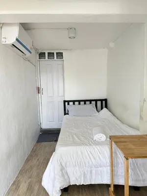 a bedroom with a bed and a wooden table at Chubby 9 single room in Bangkok