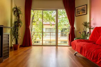 a living room with a red couch and a large window at Kiatthada Resort in Bangkok