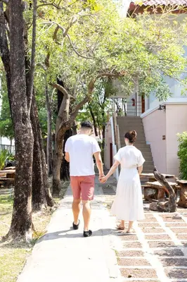 a man and woman walking down a sidewalk holding hands at Kiatthada Resort in Bangkok