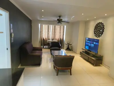 a living room with a couch and a table and a tv at Fully Furnished Omni Tower Apartments Nana - Sukhumvit soi 4 in Bangkok