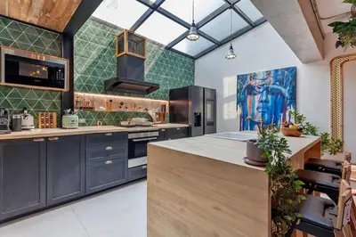 a kitchen with blue cabinets and green tiles at Thai wabi-sabi Loft in Bangkok