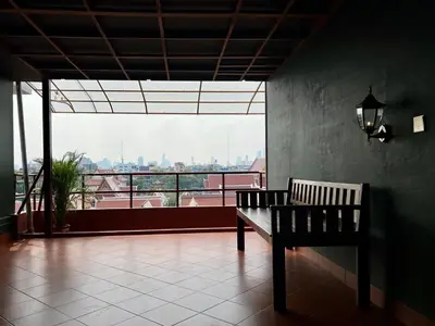a bench in a room with a view of a city at Cha Na Stay at Merry V in Bangkok