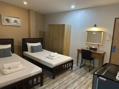 a room with two beds and a desk and a mirror at Baanfahsai in Makkasan