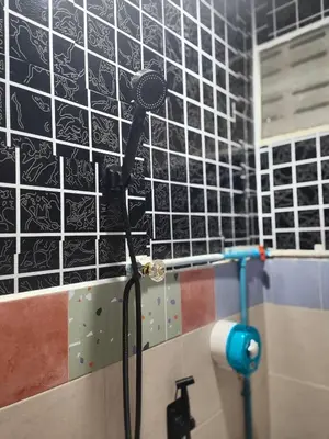 a shower in a bathroom with black and white tiles at 108 Quiet and nice fan apartment with full amenities free Wi-Fi in Bangkok