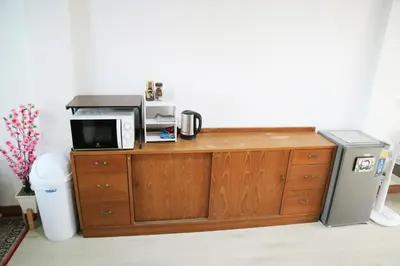 a microwave sitting on top of a wooden cabinet at Happyhouse Laksi station (PK14) in Lak Si