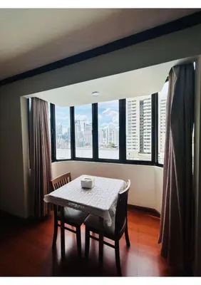 a table and chairs in a room with large windows at Affordable Serviced Apartment Nana - Omni Tower Sukhumvit location in Bangkok