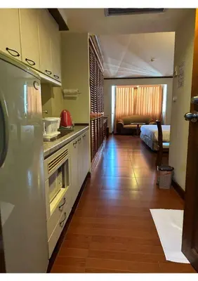 a kitchen with a refrigerator and a room with a bed at Affordable Serviced Apartment Nana - Omni Tower Sukhumvit location in Bangkok