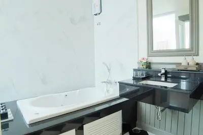 a bathroom with a sink and a large mirror at The Raya Surawong Bangkok in Bangkok