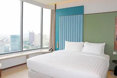 a large white bed in a room with large windows at The Quarter Ratchayothin by UHG in Bangkok