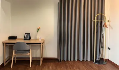 a desk with a chair next to a curtain at Arun Heaven Bangkok in Bangkok Noi