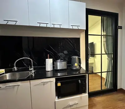 a kitchen with a sink and a microwave at Arun Heaven Bangkok in Bangkok Noi