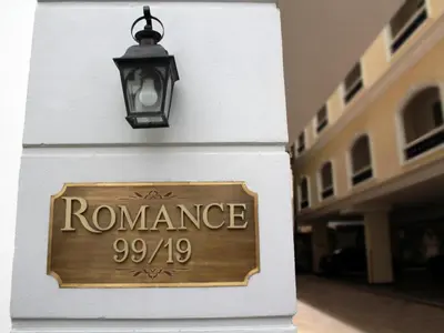 a sign on the side of a building with a light at Romance Hotel Srinakarin in Bangkok