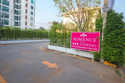 a pink sign in a parking lot next to a building at Romance Hotel Srinakarin in Bangkok