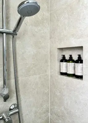 a shower with bottles of wine sitting on a shelf at Brown's Residence in Bangkok