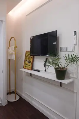 a living room with a tv on a white shelf at AboutTime Bangkok in Bangkok
