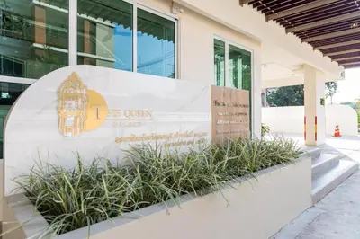 a sign in front of a building with plants at The Queen Palace in Ban Bang Talat