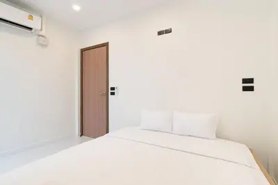a white bed in a white room with a door at Townhouse in Pratunam Bangkok in Bangkok