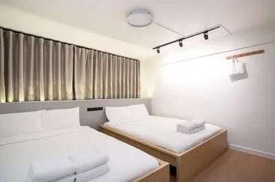two beds in a small room with a window at Townhouse in Pratunam Bangkok in Bangkok