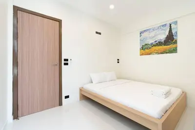 a white bedroom with a bed and a wooden door at Townhouse in Pratunam Bangkok in Bangkok