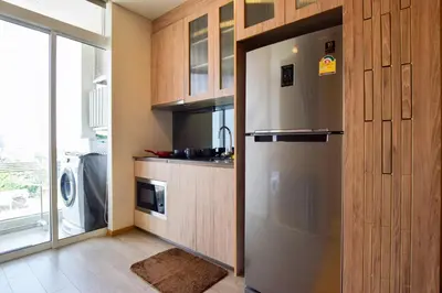 a kitchen with a stainless steel refrigerator and wooden cabinets at BTS Ekkamai-free pool-bus to pattya in Bangkok