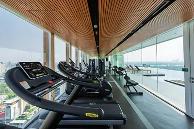 a gym with tread machines in a building with windows at BTS Ekkamai-free pool-bus to pattya in Bangkok